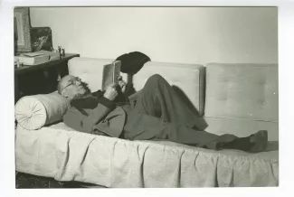 portrait photographique d’André Gide, avec lunettes, allongé sur un sofa, lisant, chez Richard Heyd, hiver 1947