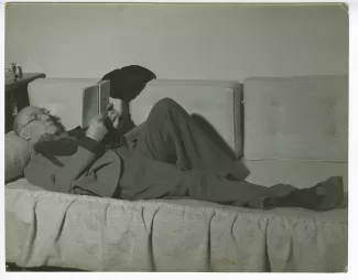 portrait photographique d’André Gide, avec lunettes, allongé sur un sofa, lisant, chez Richard Heyd, hiver 1947