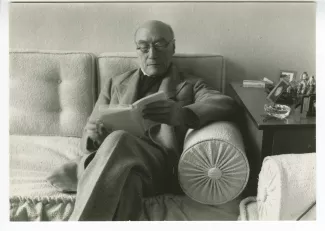 portrait photographique d’André Gide, avec lunettes, assis sur un sofa, lisant, chez Richard Heyd, hiver 1947