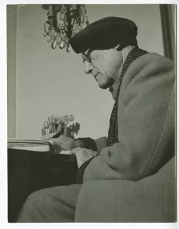 portrait photographique d’André Gide, avec lunettes et béret, de profil, attablé, écrivant, chez Richard Heyd, hiver 1947