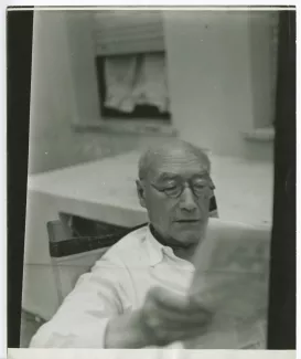 portrait photographique d’André Gide, avec lunettes, lisant un journal, en extérieur, chez les Orlandi, août-septembre 1948