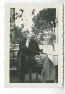 photographie d’André Gide, avec lunettes, assis sur une terrasse d'immeuble, après sa sortie de la clinique du Belvédère à Nice, été 1949