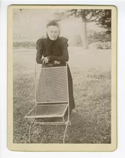 photographie de Claire Démarest, tante maternelle d'André Gide, accoudée à une chaise, dans le jardin du château de Cuverville