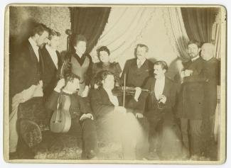 photographie de groupe où l'on reconnaît Théo Van Rysselberghe, premier à gauche, Maria Van Rysselberghe, quatrième debout au centre, Octave Maus, cinquième debout à gauche, Dario de Regoyos, premier assis à gauche, tenant une guitare, Eugène Ysaÿe, deuxi