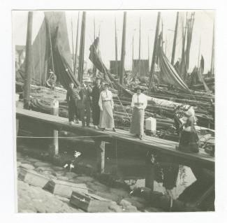 photographie montrant Théo Van Rysselberghe (au chapeau blanc), Élisabeth Van Rysselberghe (à droite) et Daisy Weber, avec des autochtones, debout sur un appontement