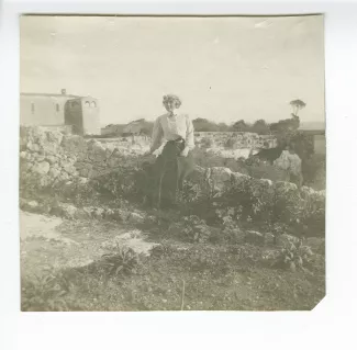 photographie de Maria Van Rysselberghe, assise sur un muret dans le jardin de l’hôtel, au bord de la latomie des Capucins, décembre 1908