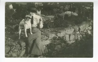 photographie-carte postale de Maria Van Rysselberghe, assise sur un muret, avec le chien Nick