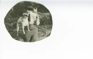 photographie-carte postale de Maria Van Rysselberghe, assise sur un muret, avec le chien Nick