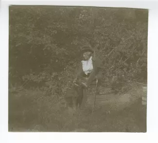 photographie de Maria Van Rysselberghe, assise sur un tronc, caressant un chien