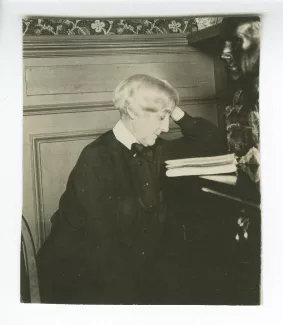photographie de Maria Van Rysselberghe, lisant, à côté du buste sculpté d'André Gide par Théo Van Rysselberghe (1918)