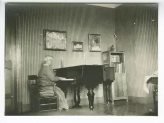 photographie de Maria Van Rysselberghe, de dos, jouant du piano, à la Bastide Franco