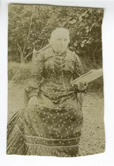 portrait photographique de Sylvie Monnom, mère de Maria Van Rysselberghe, un journal à la main, en extérieur