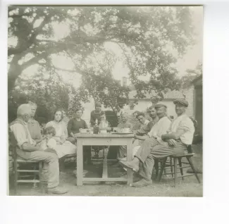 photographie montrant Élisabeth Van Rysselberghe, debout au centre, et la famille Caramello, fermiers à la Bastide Franco, attablés sous un arbre, à la Bastide Franco