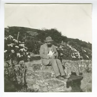 photographie d'Octave Van Rysselberghe, assis avec un chat, dans le jardin de la maison de Saint-Clair