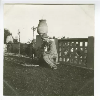 photographie d'Octave Van Rysselberghe, assis dans l'herbe avec un chat, dans le jardin de la maison de Saint-Clair