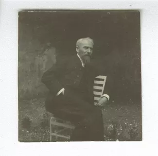 portrait photographique d'Henri-Edmond Cross, assis sur une chaise, dans le jardin de la villa Aublet, rue Laugier