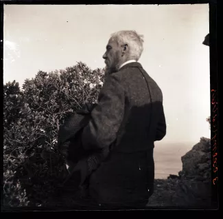 photographie d'Henri-Edmond Cross, sa veste au bras, sur un rocher surplombant la mer, printemps 1905