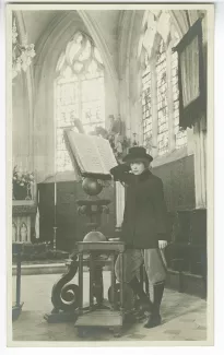 portrait photographique en pied de Lucie Delarue-Mardrus, accoudée à un antiphonaire, dans une église