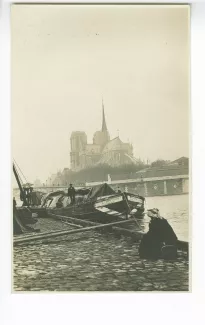 photographie de Lucie Delarue-Mardrus, assise devant une péniche, en face de Notre-Dame de Paris