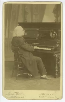 portrait photographique du compositeur Franz Liszt, assis au piano, chez lui