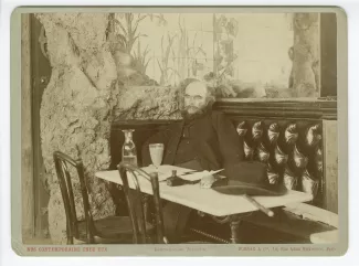 portrait photographique de Paul Verlaine, assis à une table du café François Ier, 28 mai 1892