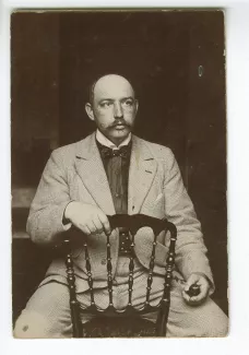 portrait photographique de Francis Vielé-Griffin, assis à califourchon sur une chaise, juin 1897