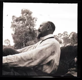 photographie d'Octave Van Rysselberghe [?], de profil, assis dans l'herbe