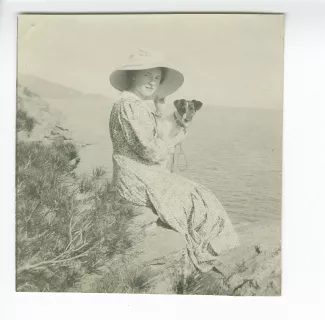 photographie de Daisy Weber, assise sur les rochers, avec le chien Nick dans les bras