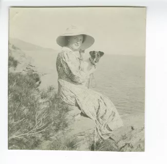 photographie de Daisy Weber, assise sur les rochers, avec le chien Nick dans les bras