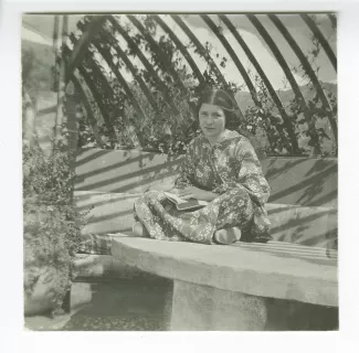 photographie de Daisy Weber, assise en tailleur, un livre en main, dans le jardin de la villa de Saint-Clair, été 1913
