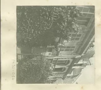 photographie d'une femme non identifiée, perchée devant la grille d'entrée de la villa Aublet, rue Laugier, avril 1902