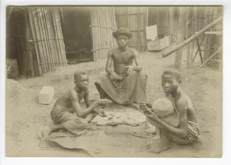 photographie de trois adolescents autochtones pesant de l'or, dans un village